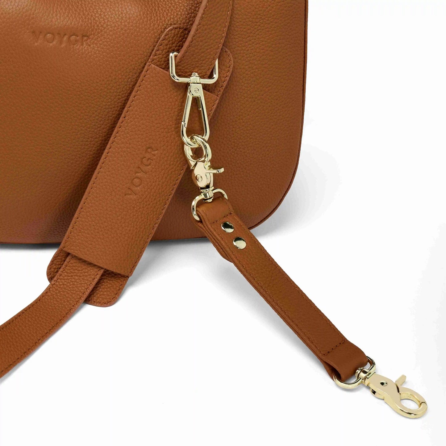 Brown leather camera bag with matching strap and gold hardware on a white background