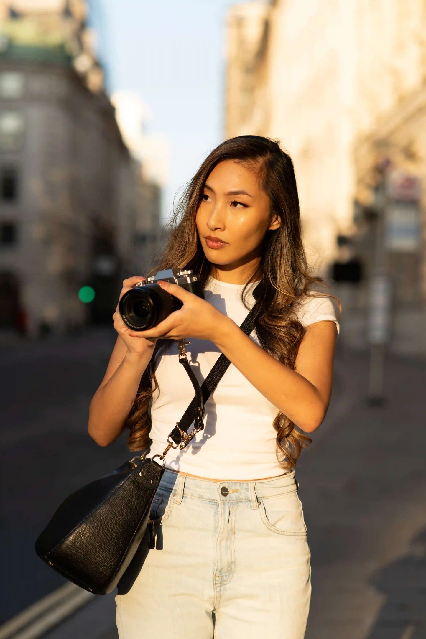 Woman holding a camera and Voygr camera bag on a city street in London