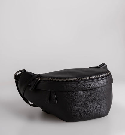 A black pebbled leather camera bag with a top zipper and a debossed Voygr London logo on the front, shown on a light gray background.