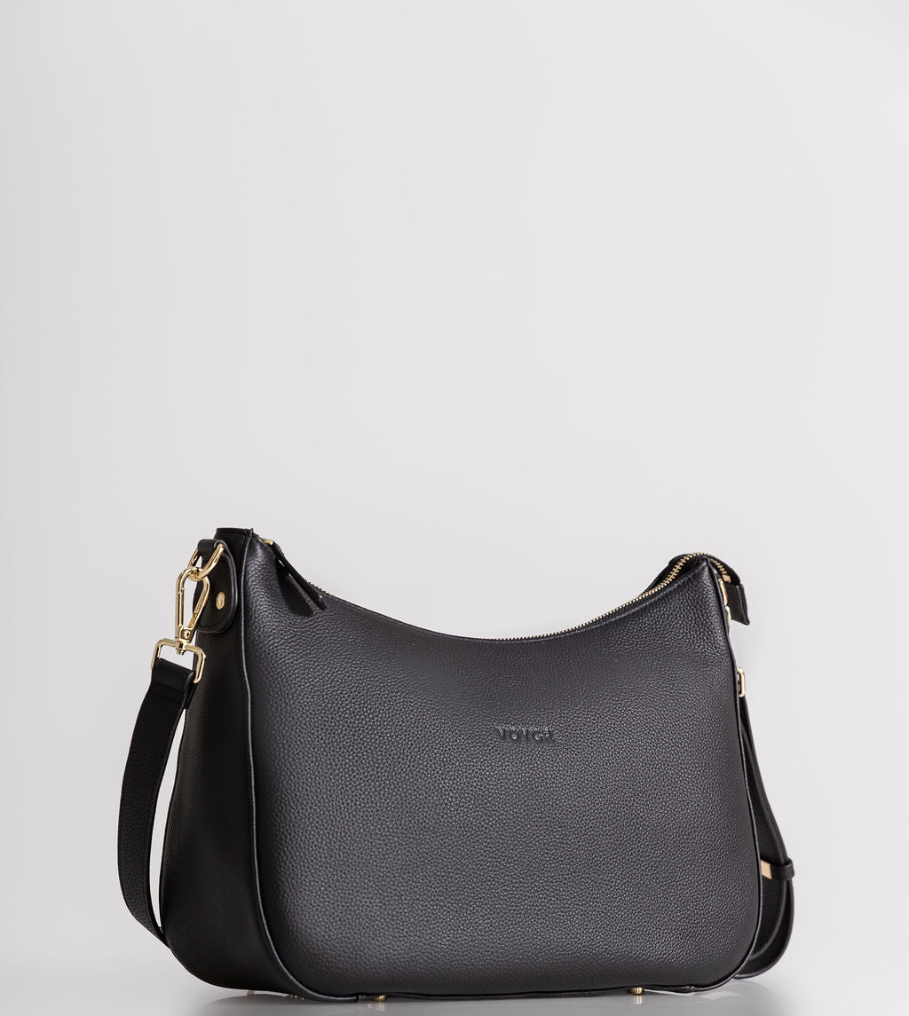 A black pebbled leather crescent-shaped shoulder bag with gold-tone hardware and a small debossed 'MCKINNEY' logo on the front, set against a plain light gray background.