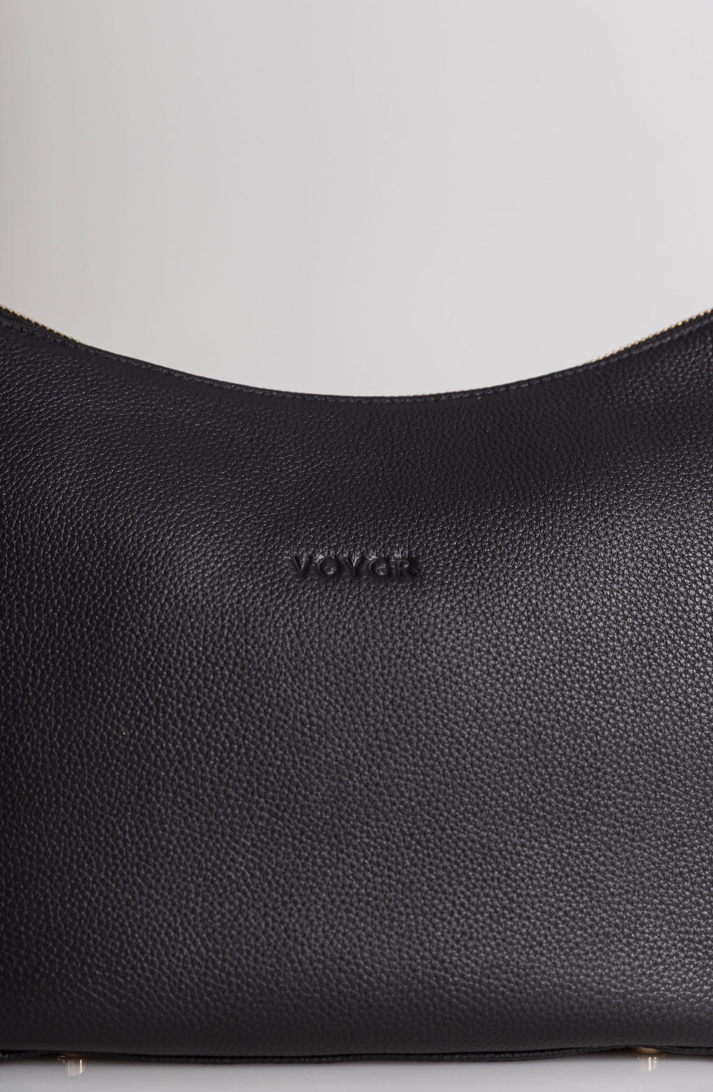 Close-up of a black pebbled leather bag with the brand name 'rover' debossed on the front, set against a neutral light gray background.